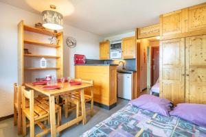 a kitchen with a table and a bed in a room at Le Vernon - Studio vue montagne près des pistes in Chamrousse