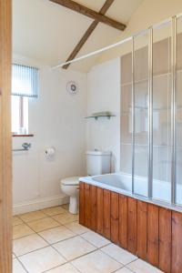 a bathroom with a bath tub and a toilet at The Stables - Holly Tree Barns in Halesworth