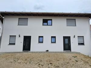 una casa blanca con puertas negras y un patio en Rustikale Ferienwohnung auf Rups Hof, en Oberhöcking