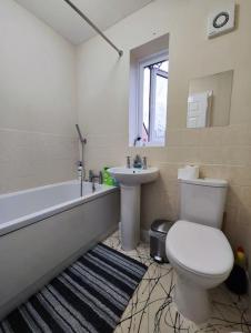 a bathroom with a toilet and a tub and a sink at Harmony in Bicester in Bicester