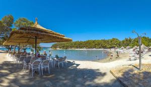 a beach with a group of people sitting under an umbrella at Chatka Daisy A,B in Pakoštane