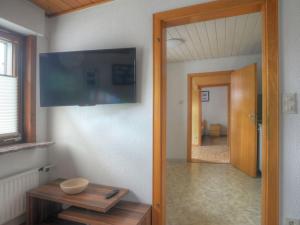 een kamer met een tv aan de muur en een tafel bij Holiday Home Peppa by Interhome in Medebach