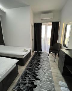 a room with two beds and a chair and a rug at Hotel FOCUS in Prilep