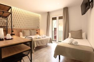 a hotel room with two beds and a table at Hotel La Milagrosa in Alicante