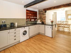 a kitchen with white cabinets and a washer and dryer at Kilderkin in Bedale