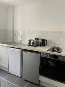 a kitchen with a counter top with a stove and a sink at Tidal Walk Cottage by the Sea in Harwich