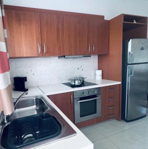 a kitchen with wooden cabinets and a stainless steel refrigerator at Four S Apartments in Mikonos