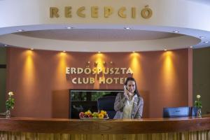 uma mulher sentada na recepção de um hotel em Erdőspuszta Club Hotel Fenyves em Debrecen