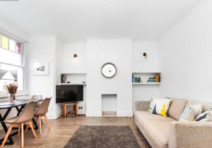 a white living room with a couch and a table at Bright and Stylish 2 Bedroom First Floor Flat in London