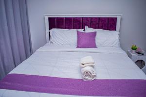 un lit violet et blanc avec tête de lit violette dans l'établissement Belaire BnB Ruaka 3, à Ruaka