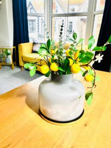 a white vase with flowers and lemons on a table at Paradise St Apartment Middle Floor 1 flight of stairs 3 bed 1 bathroom in Rhyl