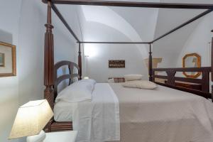 una camera con letto a baldacchino con lenzuola e cuscini bianchi di Villa Minioti Apartment C ad Arnesano