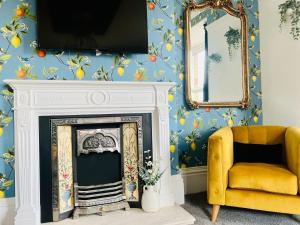 a living room with a fireplace and a yellow chair at Paradise St Apartment Middle Floor 1 flight of stairs 3 bed 1 bathroom in Rhyl