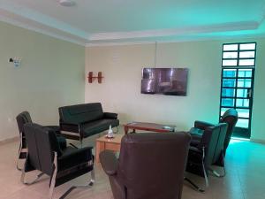 sala de estar con sillas y TV de pantalla plana en Acacia Gardens Gilgil en Gilgil