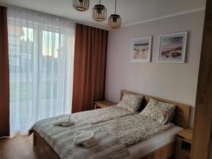 a bedroom with a bed and a large window at Apartament Wśród Kasztanów in Puck