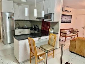 a kitchen with a glass table and two chairs at Cape Town Beachfront Accommodation in Blouberg in Bloubergstrand