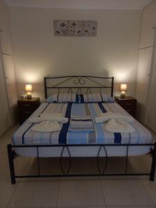 a bed with blue and white sheets and two lamps at Angela's Cute Apartment (A/C, WiFi, Little Garden) in Análipsis