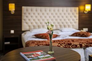 a vase of flowers on a table in a hotel room at Erdőspuszta Club Hotel Fenyves in Debrecen