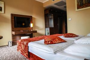 two beds with red pillows in a hotel room at Erdőspuszta Club Hotel Fenyves in Debrecen