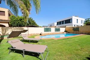 ein Hinterhof mit einem Pool und zwei Stühlen und einem Tisch in der Unterkunft Chalet con piscina en la Barrosa in Chiclana de la Frontera
