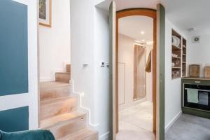 un couloir avec des escaliers et une porte avec un miroir dans l'établissement Entire Home on Victoria Park, à Londres