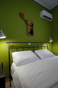 a bedroom with a white bed with a green wall at House in riviera lagonisi in Kalívia Thorikoú