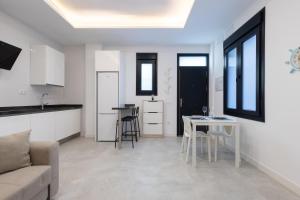 a kitchen and living room with a table and a couch at Victoria's Apartamentos in Málaga