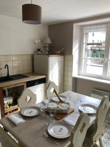 een keuken met een tafel met borden en stoelen en een raam bij La Bresse, 50 m du centre ville, appartement 4-6 personnes in La Bresse +19 foto's