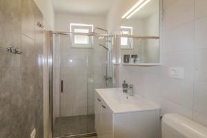 een witte badkamer met een douche en een wastafel bij studio apartment Noemi in Novigrad Istria
