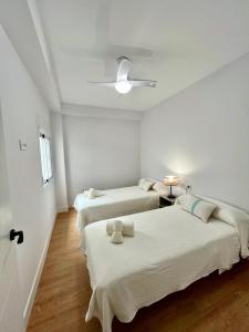 due letti in una stanza con pareti bianche e pavimenti in legno di Piso Picasso, Modern Apartment in the Heart of Malaga City a Málaga Altre 20 foto