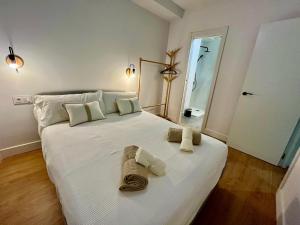 ein Schlafzimmer mit einem großen weißen Bett mit Handtüchern darauf in der Unterkunft Piso Picasso, Modern Apartment in the Heart of Malaga City in Málaga