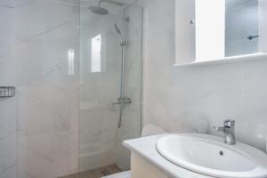 a white bathroom with a shower and a sink at Port House in Kos