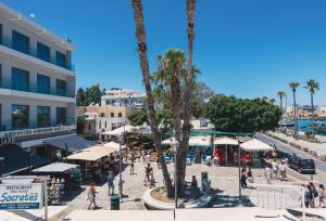 a group of people walking around a plaza with palm trees at Port House in Kos
