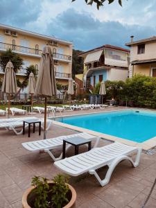 a swimming pool with chairs and umbrellas next to a hotel at Central Hotel in Parga