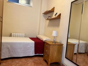 Dormitorio pequeño con cama y espejo en HABITACIÓN DOBLE o TRIPLE CORAZON DE RUZAFA, en Valencia