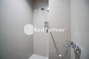 a shower stall in a bathroom with a red partner sign at Indah Residence Syariah Mitra RedDoorz in Jakarta +46 photos