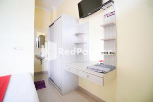 a bedroom with a dressing table and a tv on a wall at Indah Residence Syariah Mitra RedDoorz in Jakarta