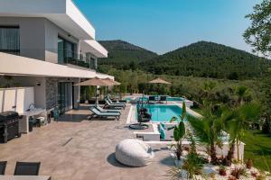 a villa with a swimming pool and mountains in the background at Nooa Villas in Skala Rachoniou