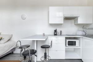 een witte keuken met 2 stoelen en een tafel en een bed bij Magnifique studio au coeur de Vincennes in Vincennes
