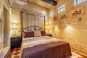 a bedroom with a bed and a stone wall at Stunning Valletta Palazzino in Valletta