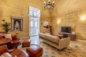 a living room with leather furniture and a tv at Stunning Valletta Palazzino in Valletta