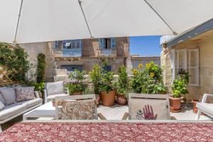 eine Terrasse mit einem weißen Sonnenschirm, Stühlen und Pflanzen in der Unterkunft Stunning Valletta Palazzino in Valletta
