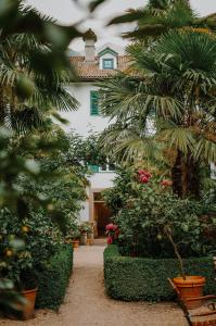 a garden with palm trees and flowers in front of a building at Ottmanngut Suite and Breakfast in Merano