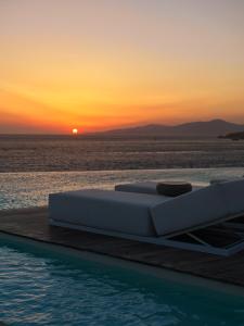 uma cama ao lado de uma piscina com um pôr-do-sol em Kouros Hotel & Suites em Míconos