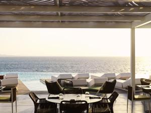 a patio with tables and chairs and the ocean at Kouros Hotel & Suites in Mýkonos City