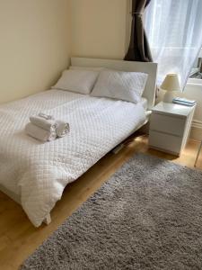 1 dormitorio con cama con sábanas blancas y alfombra en City gem, en Londres