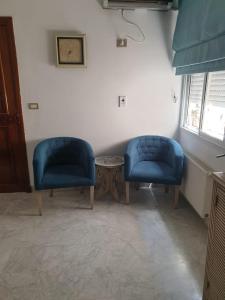 dwa niebieskie krzesła i stół w pokoju w obiekcie Appartement s+2 au plein coeur de sousse w Susie