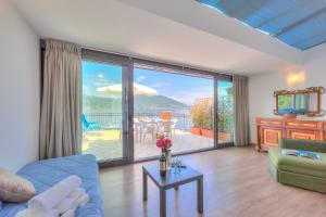una sala de estar con una gran puerta corredera de cristal y un patio. en Red House Terrace Private Beach - Happy Rentals, en Baveno