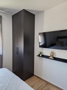 - une chambre avec un lit et une télévision murale dans l'établissement Apartment Luka, à Privlaka
