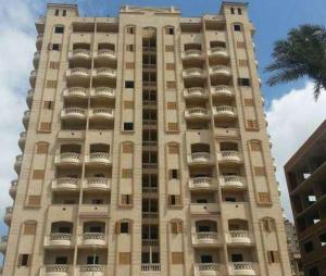 a large tall building with balconies and a palm tree at شقة فاخرة في كمبوند ميامى جراند بلازا الإسكندرية in Alexandria